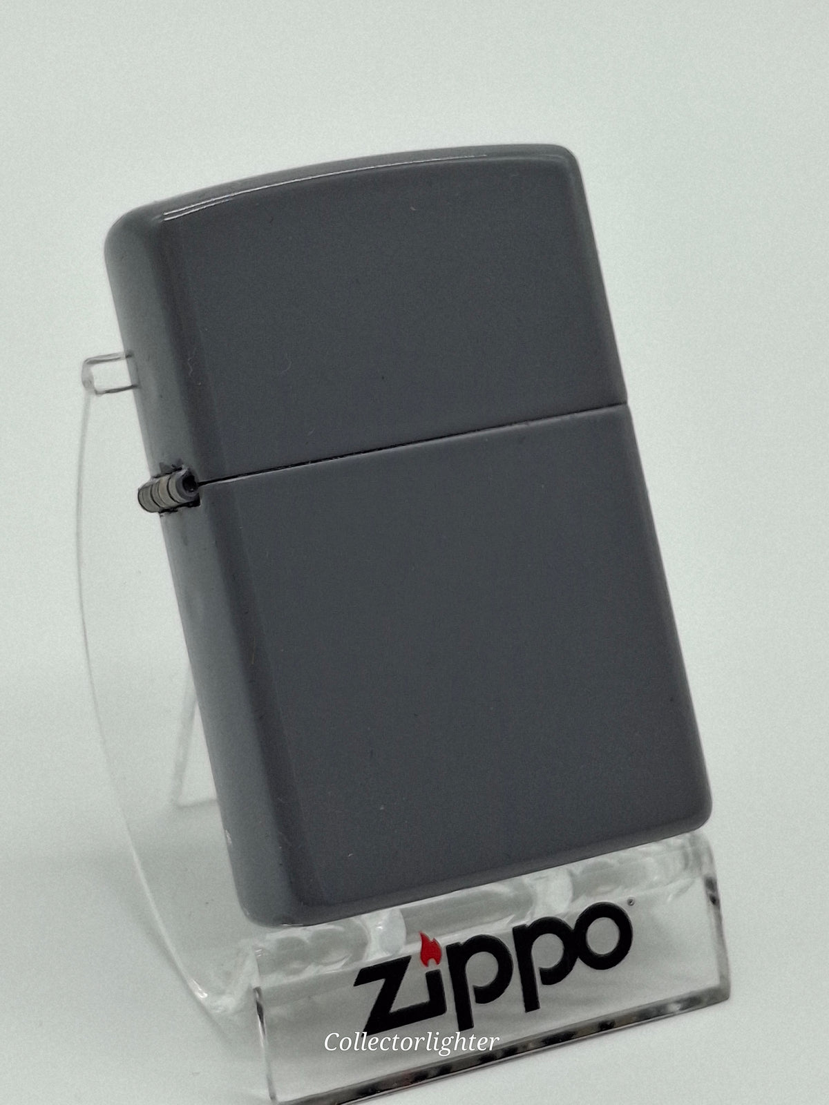 Zippo Flat Grey Regular, schräge Vorderansicht mit schlichtem grauem Gehäuse und Scharnier