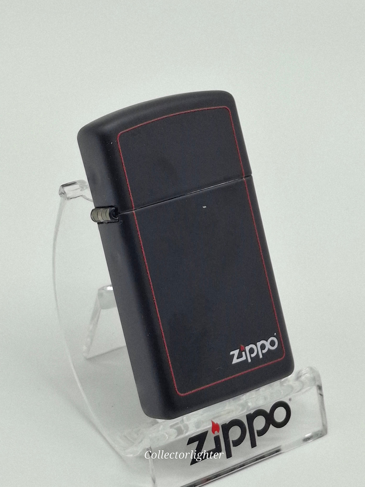 Zippo Black Matte with Zippo Border Slim Line 60001438, schräge Vorderansicht mit mattschwarzem Gehäuse, rotem Rahmen und Zippo-Logo