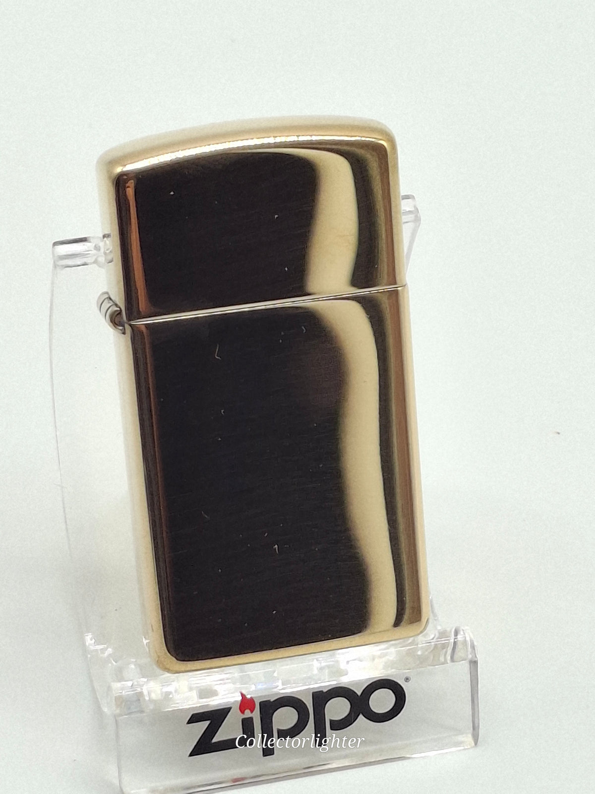 Zippo Brass polished Slim Line 60001177, schräge Vorderansicht mit spiegelndem Messinggehäuse und Scharnier
