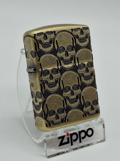 Zippo Skulls Design Multi Cut 60007234, schräge Vorderansicht mit tief gravierten Totenköpfen und antikem Messingfinish